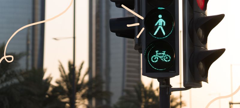 Traffic light with green walk signal and green bike signal lit up with palm tree in the background